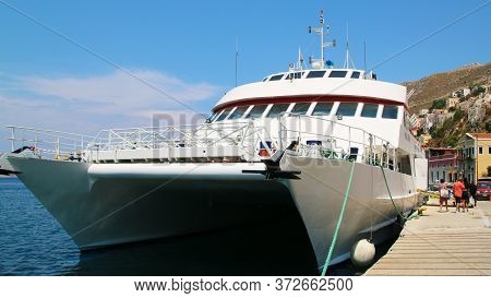 Symi, Greece - June 12, 2019: Travelers Of King Saron Passenger Catamaran Come Ashore In The Port Of