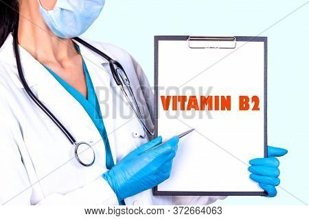Vitamin B2 Text Is Written On A Tablet Which The Doctor Holds In A Medical Gown And Gloves. Medical 