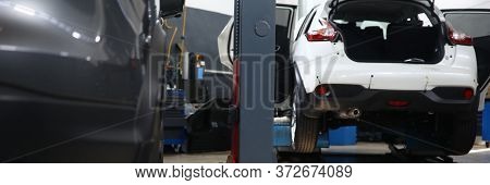 Close-up View Of Service Station Garage With Foreign Cars. Red Jackscrew Or Mechanical Lift. Fixing 