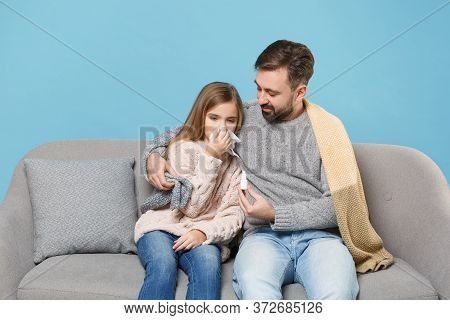 Man In Knitted Sweater With Sick Child Baby Girl. Father Little Daughter Isolated On Blue Background