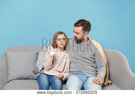 Man In Knitted Sweater With Sick Child Baby Girl. Father Little Daughter Isolated On Blue Background