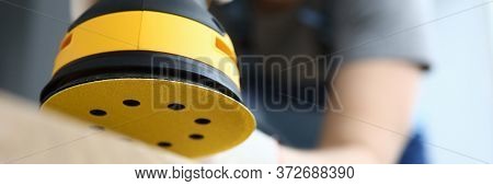 Male Handy Man Hold Yellow Grinder With Disc Sander In Hand Closeup Background. Professional Educati