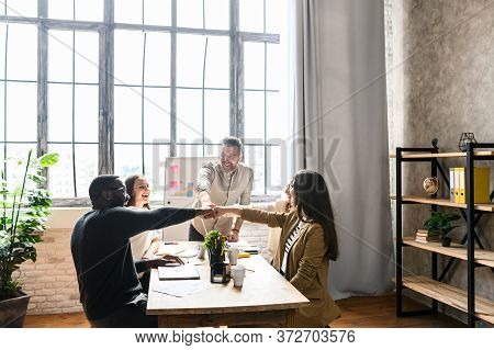 Creative And Cheerful Multiracial Team At The Office Laughing And They Stack Their Fist Together As 