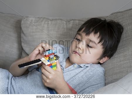 6-7 Yearold Boy Lying On Sofa Playing With Building Coloufull Blocks, Young Boy Concentrated With Cr