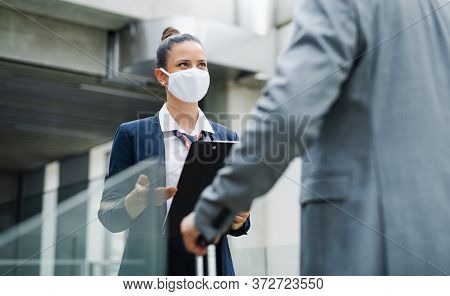 Flight Attendant Talking To Unrecognizable Businessman On Airport, Wearing Face Masks.