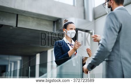 Flight Attendant Talking To Businessman On Airport, Wearing Face Masks.