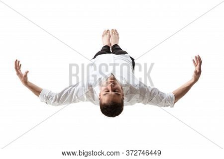 Mid-air Beauty Cought In Moment. Full Length Shot Of Young Man Hovering In Air And Keeping Eyes Clos