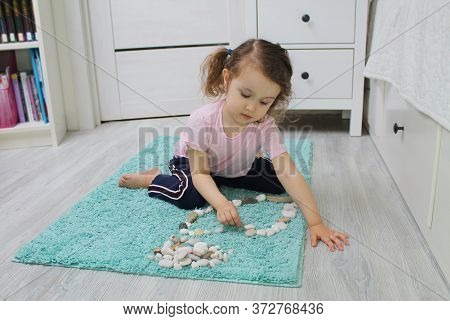 The Child Plays With Stones, Attentively Listens To The Task Of An Adult. The Concept Of Developing 