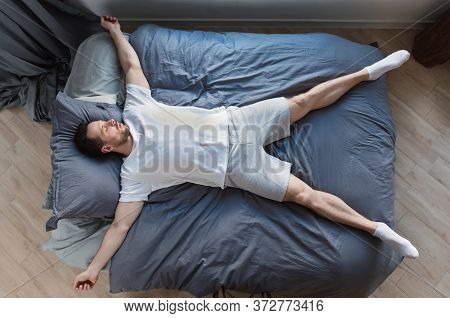 Fast Asleep Man Sleeping Lying On His Back In Bed Resting At Home. Healthy Sleep Concept. Top View