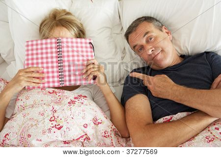 Ennuyé de recherche Senior homme couché dans son lit à côté du livre de lecture Senior femme