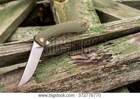 Knife In A Bent Position On Wooden Boards. Unusual Shape Of A Knife.