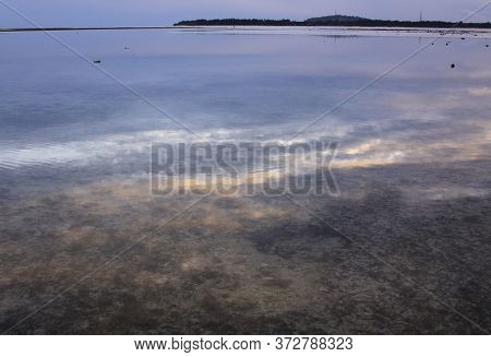 Cloudy Sky Reflected In Calm Water At Low Tide Before Dusk And Gili Meno Island Silhouette In The Di