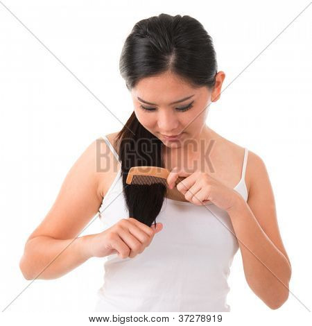 Young Asian female pettinando i capelli su sfondo bianco
