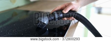 Close-up Of Persons Hand Cleaning Cookstove Display With Nozzle Of Vacuum Cleaner. Male In Protectiv