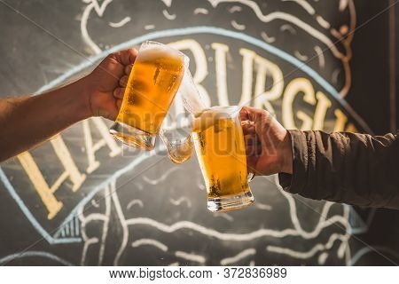 Two People Toasting With Mugs Full Of Chopp, With Background;