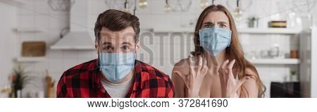 Shot Of Angry Couple In Medical Masks Screaming While Looking At Camera
