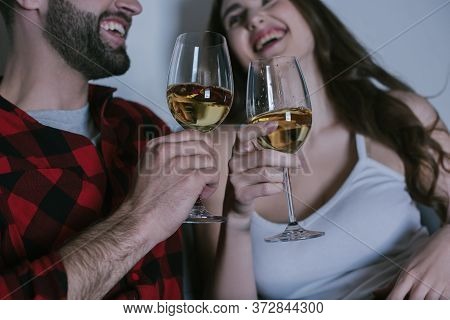 Focus Of Young Couple Laughing While Holding Glasses Of White Wine