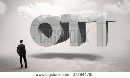 Rear view of a businessman standing in front of OTT abbreviation, modern technology concept