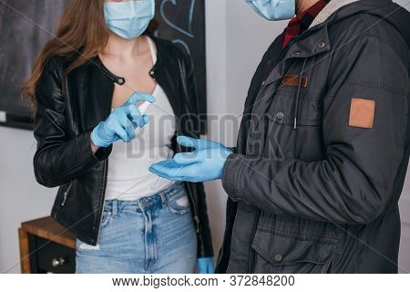 View Of Couple In Medical Masks And Latex Gloves Using Antiseptic Spray