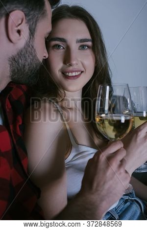 Girl Smiling At Camera While Sitting Near Boyfriend With Glasses Of White Wine