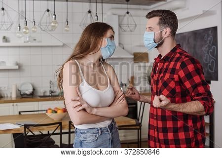 Couple In Medical Masks Quarreling While Girl Standing With Crossed Arms And Man Holding Clenched Fi