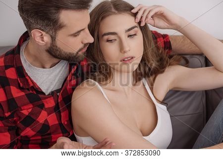 Man Showing Shrug Gesture While Sitting On Sofa Near Upset Girl