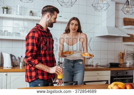 Girl Holding Plates With Delicious Croissants Near Boyfriend Holding Glass Of Orange Juice