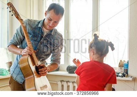 Closeup Mans Hand Changing Strings On His Old Acoustic Guitar.