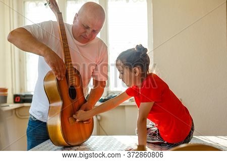Closeup Mans Hand Changing Strings On His Old Acoustic Guitar.