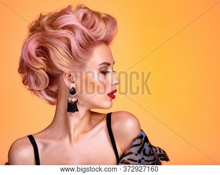 Beautiful woman with creative hairstyle, vivid makeup. Fashionable girl. Beautiful face of young woman with red lips. Stunning blonde girl. Bright eye makeup. Attractive caucasian model with earrings