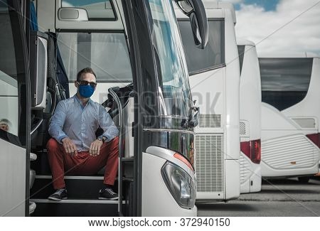 Caucasian Bus Driver In His 40s Seating On The Coach Bus Entry Stair. Virus Outbreak Lockdown Time. 