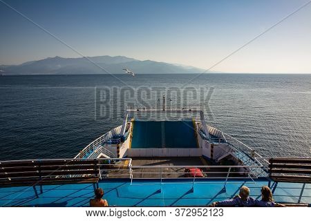 A Couple And A Single Woman Sitting On A Ferry Boat's Deck On The Open Sea On A Sunny Summer Day, A 