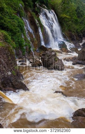 Waterfall Landscape View Of Fresh Water Flows Over A Vertical Drop To Green Field In Tropicana