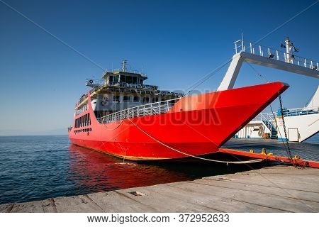 Red Ferry Boat With An Open Ramp And Empty Car Deck, Moored To The Harbour, Thassos Island, Greece
