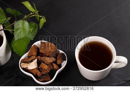 White Ceramic Cup Of Healing Infusion Of Birch Mushroom Chaga, Bowl With Chaga Pieces And Birch Leav