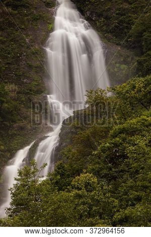 Waterfall Landscape View Of Fresh Water Flows Over A Vertical Drop To Green Field In Tropicana