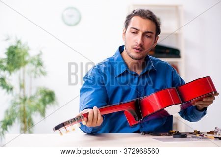Young male repairman repairing guitar