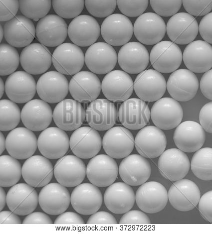 Closeup Of White Plastic Bb's Lined Up On Flat Background