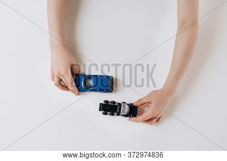 Two Toy Cars In Children's Hands On A White Background