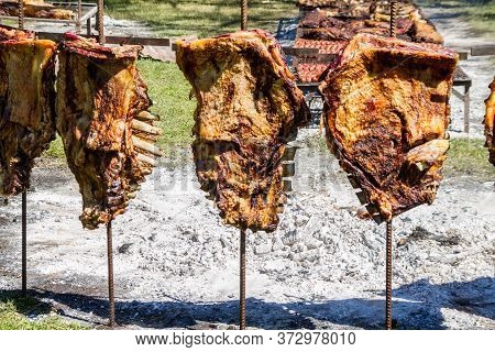 Cow Ribs To The Cross Roasting On The Coals, Typical Of The Argentine Countryside