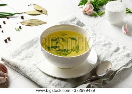 Chicken Broth With Spices, Greens, Garlec, Parsley, Onion In Bowl On White Table. Copy Space. Close 