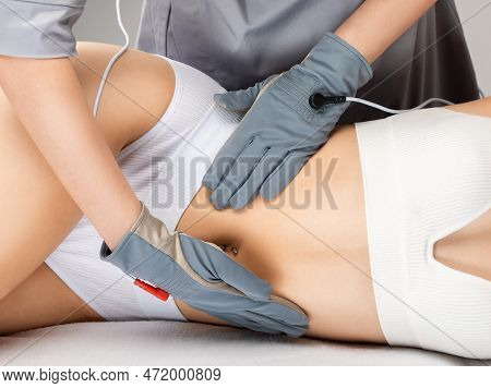 Doctor Cosmetologist Makes A Microcurrent Massage Procedure On The Belly Of A Beautiful Girl In A Be