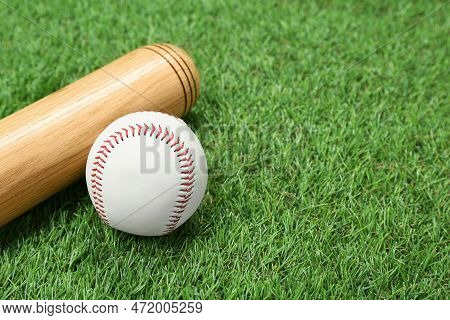 Wooden Baseball Bat And Ball On Green Grass, Closeup. Space For Text
