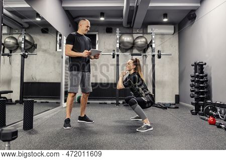 A Woman In An Electric Muscular Suit To Simulate Exercising In A Training Center. A Young Female In 