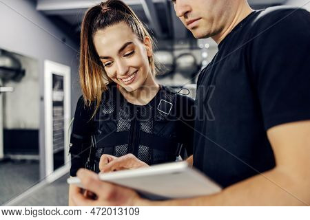 Satisfactory Training Results For Electrical Muscle Stimulation Training. Woman In A Black Ems Suit 