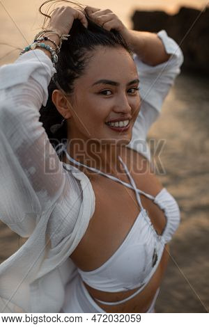 Portrait Of Young Tanned Sexy Woman In White Swimsuit With Smile Looking At Amera Against The Backgr