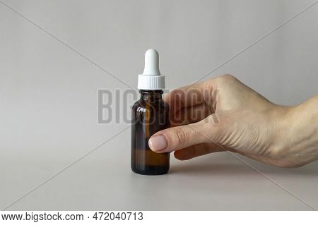 The Young Womans Hand Holds A Bottle With A Dropper, With An Oil Or Serum For Facial And Body Care.