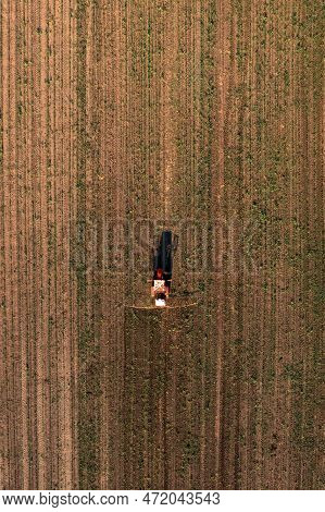 Aerial Shot Of Agricultural Tractor With Crop Sprayer Attached Spraying Herbicide Chemical Over Corn