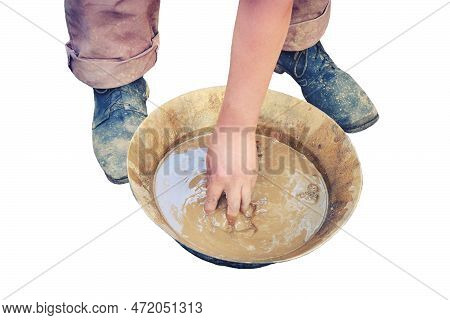 A Man Washes Gold Sand In A Copper Tray, Isolated On A White Background. Washing Of Gold In The Tray