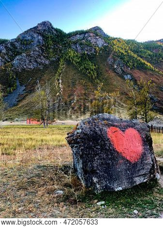 A Large Stone With A Heart On The Background Of Mountains.